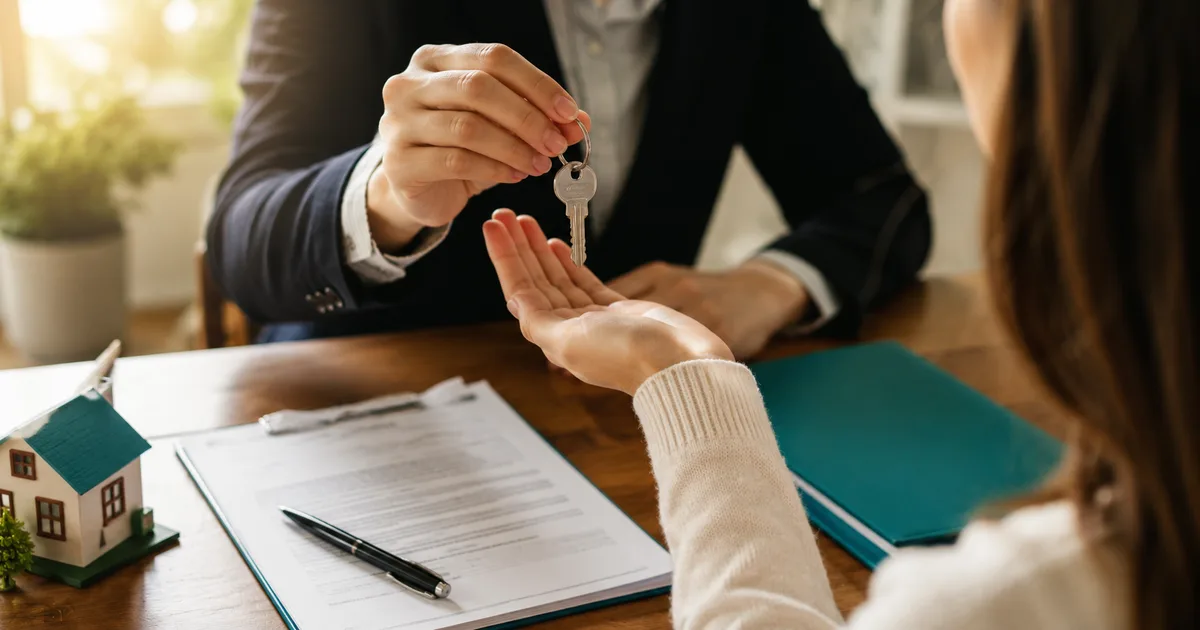 Florida first-time home buyer receiving house keys over grant paperwork